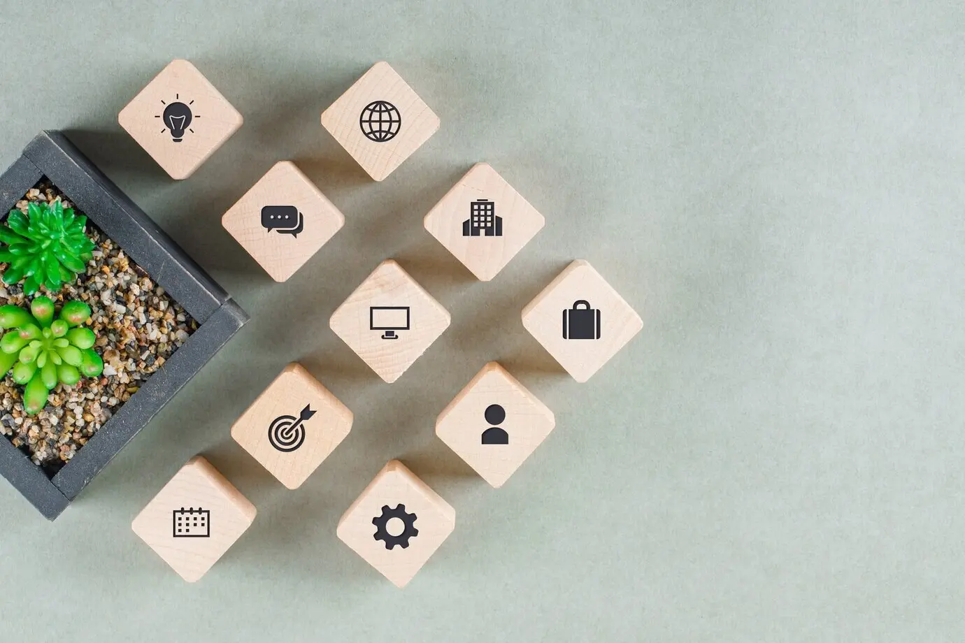 Business concept featuring wooden blocks with icons and a green plant.