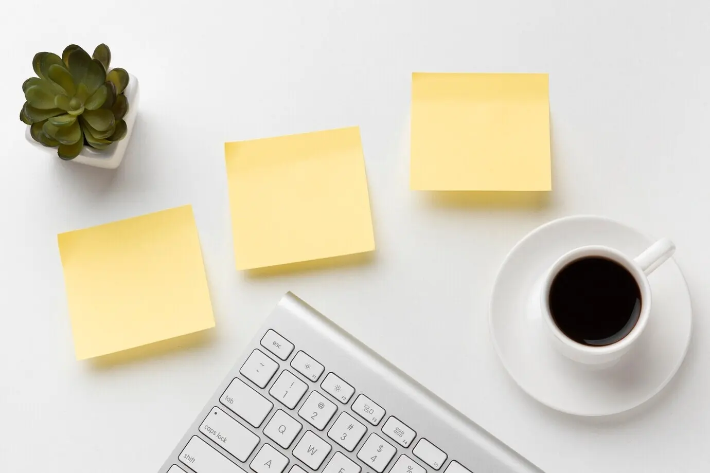 Overhead view of assorted office desk items with blank Post-it notes