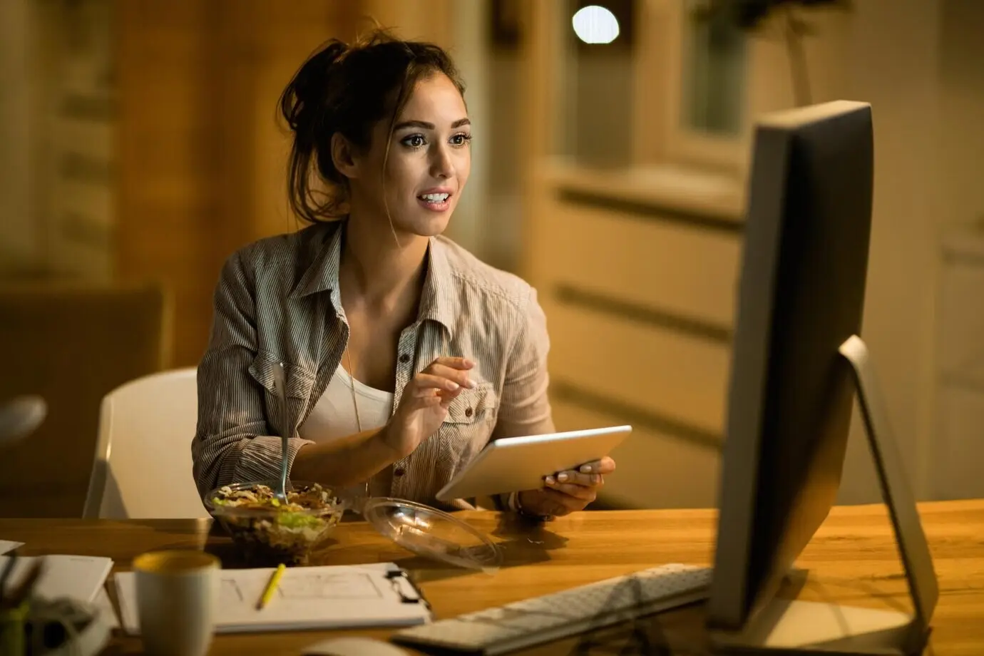 At home at night, a female freelancer uses a touchpad while reading email on a desktop PC.